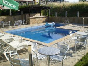 a pool with white chairs and tables and a table and chairs at Хотел Лагуна in Chernomorets