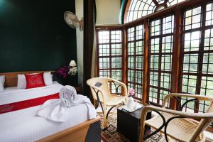 una camera da letto con un letto, sedie e finestre di LikeMyHome Homestay Mysore a Mysore