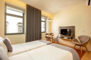 ポルトにあるFeel Porto Codeçal Apartmentsのベッド2台、テーブル、テレビが備わるホテルルームです。