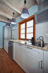 a kitchen with white cabinets and a sink and two lights at Domek na Stoku in Kazimierz Dolny