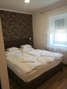 duże łóżko w sypialni z oknem w obiekcie Halász Vendégház w mieście Szilvásvárad +6 zdjęć