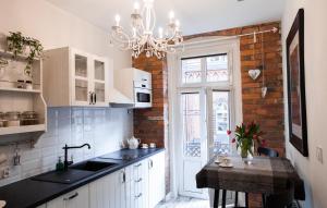 a kitchen with white cabinets and a brick wall at Apartamenty Pocztowa in Bydgoszcz