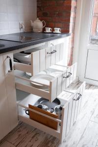 a kitchen with white cabinets with pots and pans at Apartamenty Pocztowa in Bydgoszcz