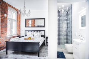 a bedroom with a bed and a bathroom with a chandelier at Apartamenty Pocztowa in Bydgoszcz