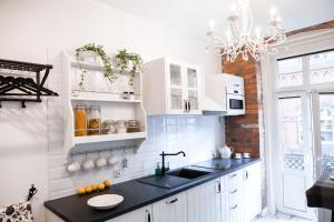 a kitchen with white cabinets and a sink at Apartamenty Pocztowa in Bydgoszcz