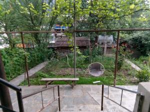 a garden with a bench and a bird cage at Guest House Borjomi in Borjomi