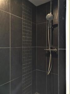 baño con ducha de azulejos negros en Derrière la plage : suite, patio et pergola en Le Bois-Plage-en-Ré