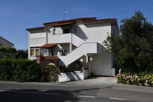 una casa blanca con una escalera blanca delante de ella en Apartments Josip, en Rab