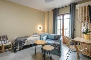 a bedroom with a blue couch and a bed and a table at Oasis Apartments in Tolo