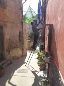 un hombre en una escalera que fija una bandera a un edificio en Da Giusè, en Trebiano