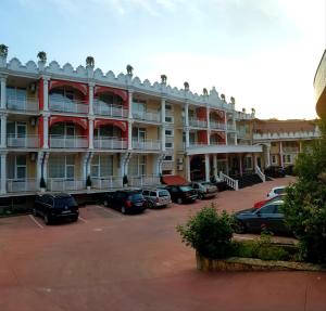 een groot gebouw met auto's geparkeerd op een parkeerplaats bij Hotel Elit Palace and SPA in Balchik