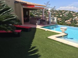 un patio trasero con piscina y una casa en Villa Goonie, en Les Issambres