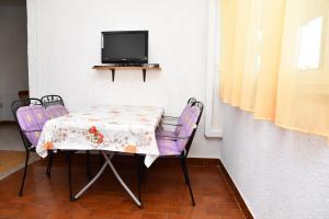 a table with two chairs and a tv on a wall at Apartments Josip in Rab