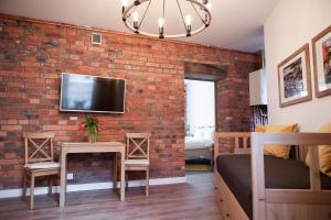 a brick wall in a bedroom with a bed and a tv at Apartamenty Pocztowa in Bydgoszcz