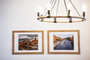 two pictures hanging on a wall with a chandelier at Apartamenty Pocztowa in Bydgoszcz