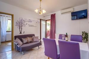 a dining room with a table and purple chairs at Apartment Budinic in Mali Lošinj