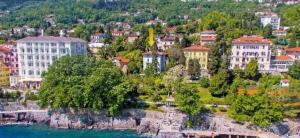 a group of buildings on a hill next to the water at Studio apartman Villa Gianna in Lovran