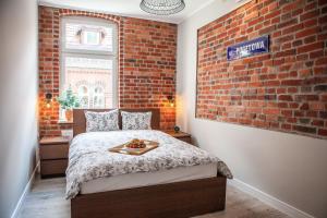 a bedroom with a bed with a brick wall at Apartamenty Pocztowa in Bydgoszcz