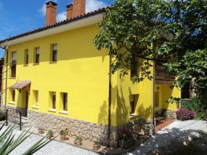 a yellow house with a stone wall at Apartamentos Rurales Pernús in Colunga