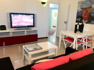 sala de estar con TV, sofá y mesa en Brisa de Mar apartamento Costa da Caparica, en Costa da Caparica