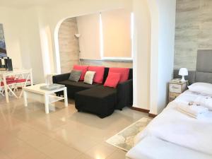 sala de estar con sofá negro y almohadas rojas en Brisa de Mar apartamento Costa da Caparica, en Costa da Caparica