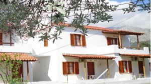 a white house with red windows and mountains in the background at Studios Calvinos in Marathokampos