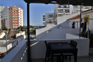 une table et des chaises noires sur un balcon avec un parasol dans l'établissement Casa Da Praia "AL", à Monte Gordo