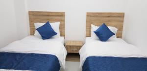 2 letti con cuscini blu in una stanza di Duqm Suites a Duqm