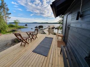una terraza de madera con sillas y una mesa en la playa en Kesämökki Tanela en Leppälahti