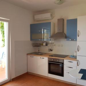 a kitchen with white cabinets and a stove top oven at Apartmani Čulek in Rukavac