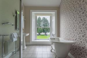 uma casa de banho com uma banheira, um lavatório e uma janela em Mansion House Llansteffan em Carmarthen