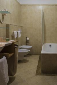 łazienka z dwiema toaletami, wanną i umywalką w obiekcie Hotel Beatrice w mieście Este