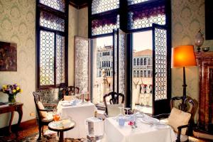 een eetkamer met tafels en stoelen en een raam bij Palazzetto Pisani Grand Canal in Venetië