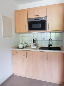 a kitchen with wooden cabinets and a microwave at Ferienwohnung Fischer in Kurort Gohrisch