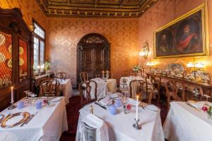 una sala da pranzo con tavoli e sedie bianchi e un dipinto di Palazzetto Pisani Grand Canal a Venezia