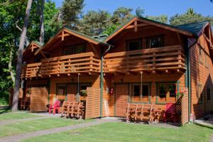a log cabin with chairs in front of it at NATURA PARK Ustronie Morskie - domki, apartamenty in Ustronie Morskie