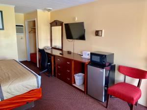 a hotel room with a bed and a desk with a television at Budget Inn Mifflintown in Mifflintown