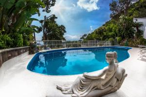 una estatua se sienta frente a una piscina en Ischia Dream Visions, en Isquia