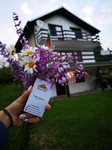 a person holding up a bunch of flowers in front of a house at Вила Рай in Voneshta Voda