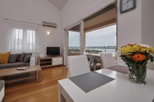 ein Wohnzimmer mit einem Sofa und einem Tisch mit Blumen in der Unterkunft Buonocore apartment in Trogir