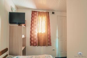 a bedroom with a bed and a television and a window at Casa Ana Maria in Vama Veche