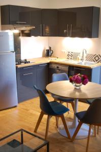 eine Küche mit einem Tisch und Stühlen sowie eine Küche mit einem Kühlschrank in der Unterkunft PETIT GITE EN BRACONNE in La Rochette