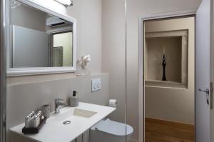 a white bathroom with a sink and a mirror at Angelo d'Oro Apartment Monte in Rovinj