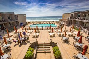 - une piscine avec des tables et des chaises et l'océan dans l'établissement Royal Atlantic Beach Resort, à Montauk