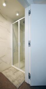 a glass shower door in a bathroom with marble walls at Studio Koksijde in Koksijde