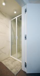 een glazen douchedeur in een badkamer met marmeren muren bij Studio Koksijde in Koksijde