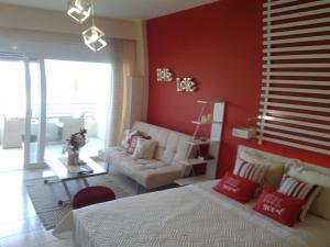 een woonkamer met een witte bank en rode muren bij Sea view cozy studio near center of Rethymno town in Rethimnon