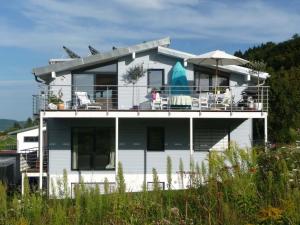 a white house with chairs and an umbrella at Haus Bodenseeblick in Bodman-Ludwigshafen
