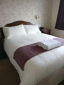 a large bed with white sheets and a brown blanket at Brook Cottage in Portree
