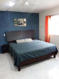 a bedroom with a bed with a blue wall at AMBAR Rooms in Campeche
